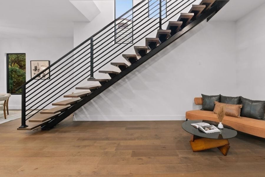 Finished modern indoor staircase with dark wood treads and a sleek black horizontal metal railing.