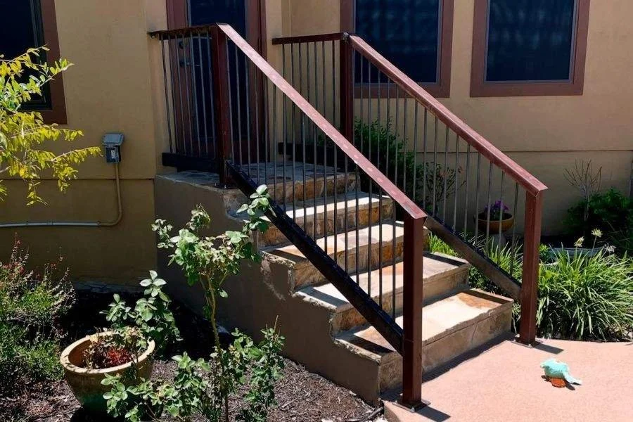 Outdoor metal stair railing with brown handrail
