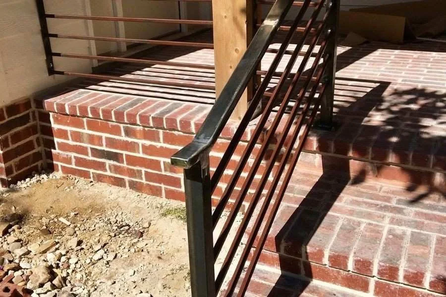Modern black horizontal stair railing on brick steps