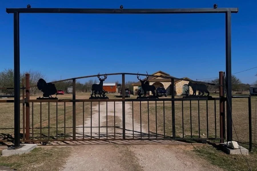 Decorative ranch-style metal driveway gate with wildlife design