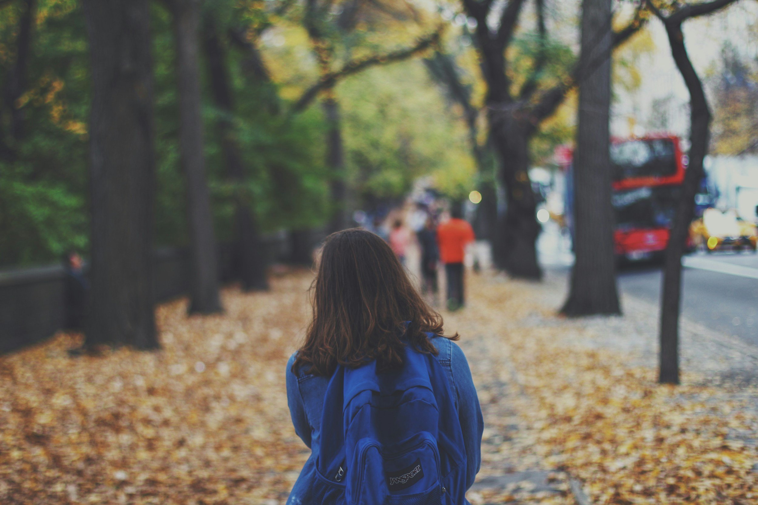 A student walking home from school during the autumn season.