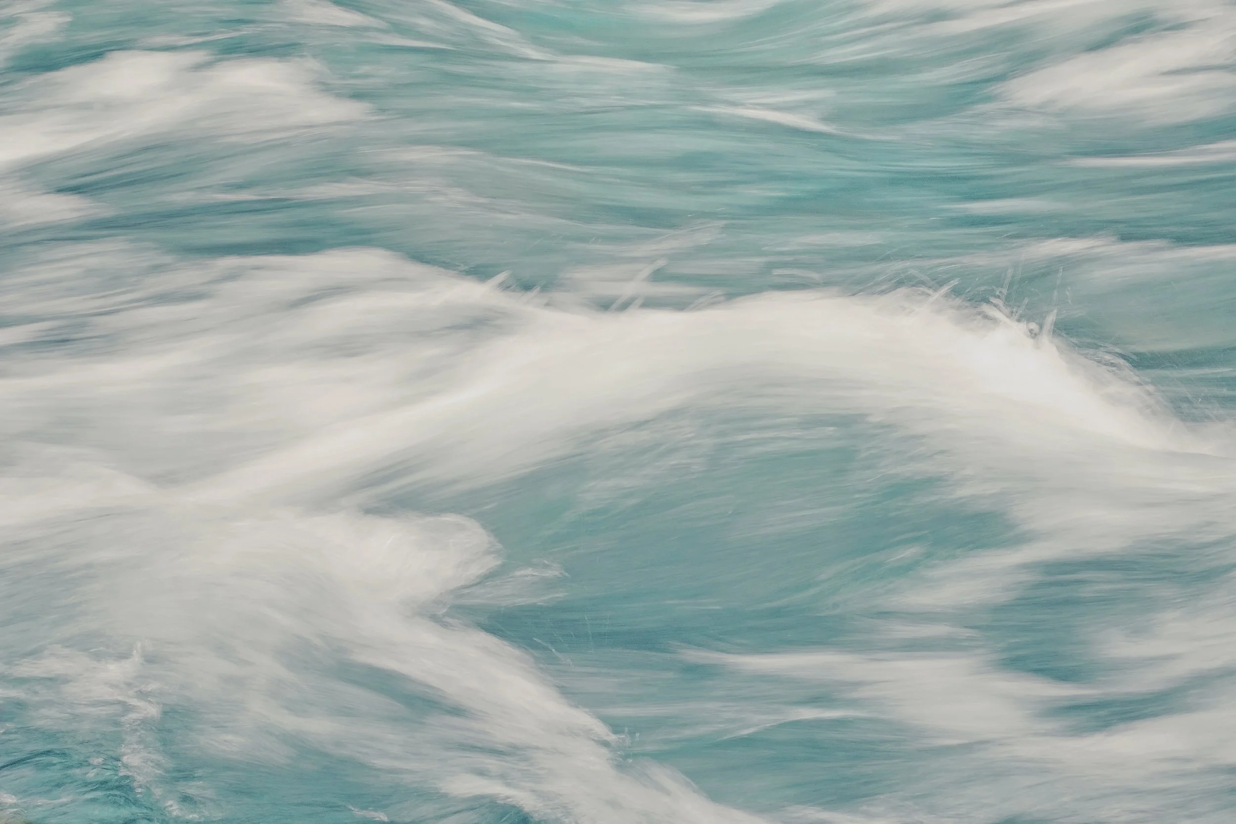 Close-up of turbulent ocean waters with white foam and swirling waves.