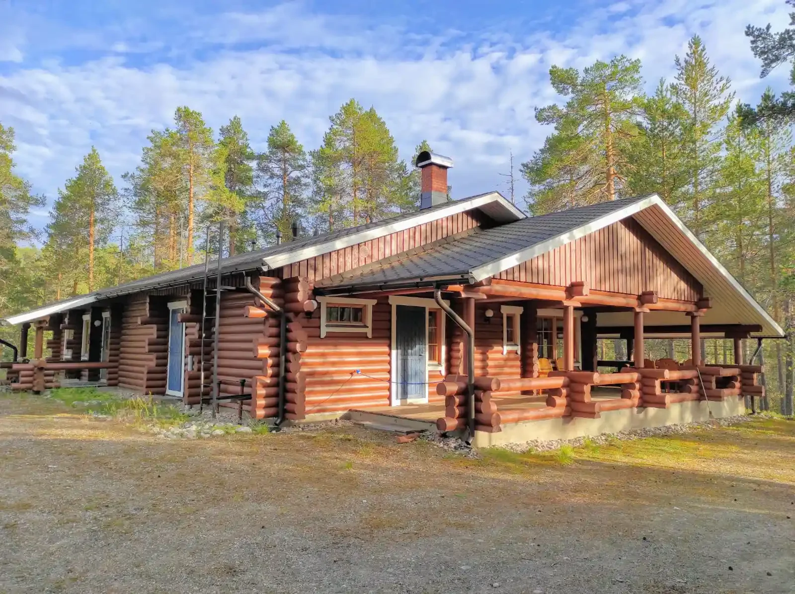 Log cabin with a porch in a wooded area during daytime.