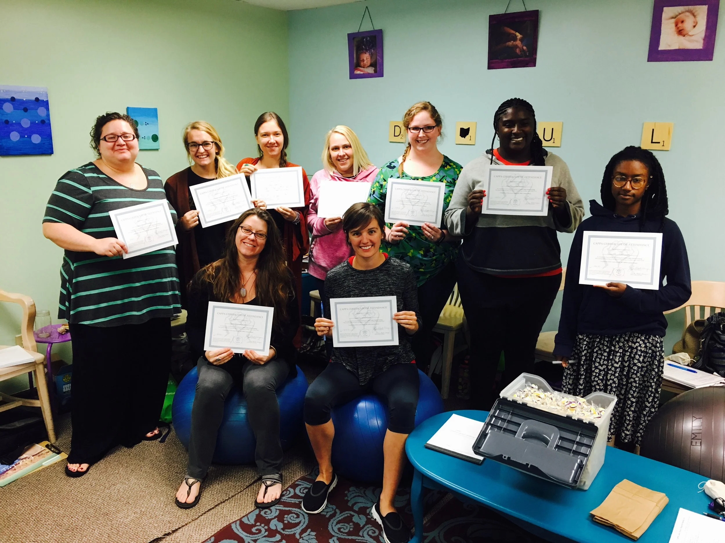 Group of doulas posing indoors while holding certificates of completion