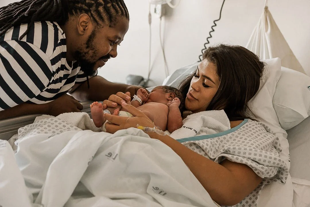 Parents holding their newborn baby in a hospital bed after birth