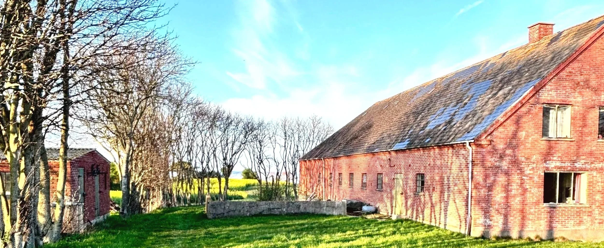 GOLFHUSET auf Ærø, rotes Backsteingebäude mit Garten und Blick in die offene Landschaft, zukünftiger Ort für Retreats und Arbeitsphasen mit Blick aufs Meer