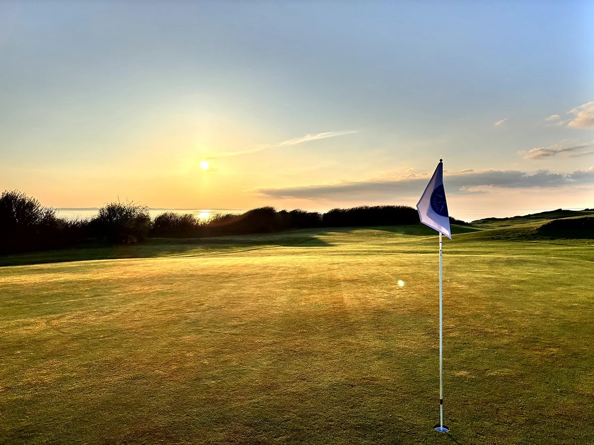 Golfloch mit Fahne im Sonnenuntergang auf dem Ærø Golf Club