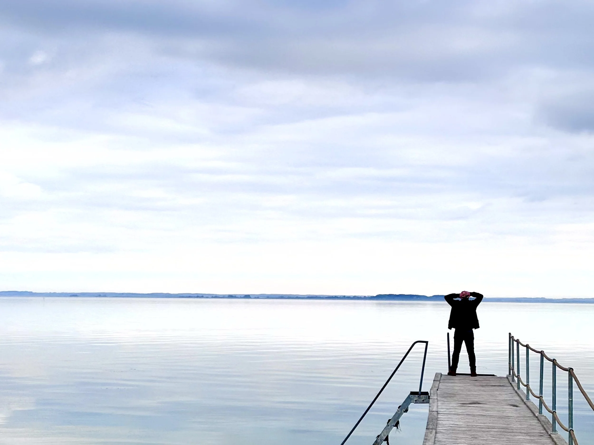 Andreas lütke, Gründer von Ærø Retreats steht am Ende eines Badestegs und blickt gedankenverloren über das ruhige Meer. Zeit für Fokus, Entspannung und Regeneration.
