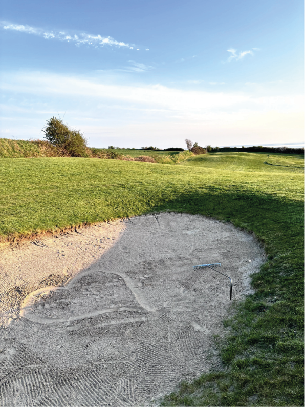Bunker auf dem Golfplatz von Ærø mit gepflegten Sandflächen und Fairway. Ein Herz ist in den Sand gemalt.