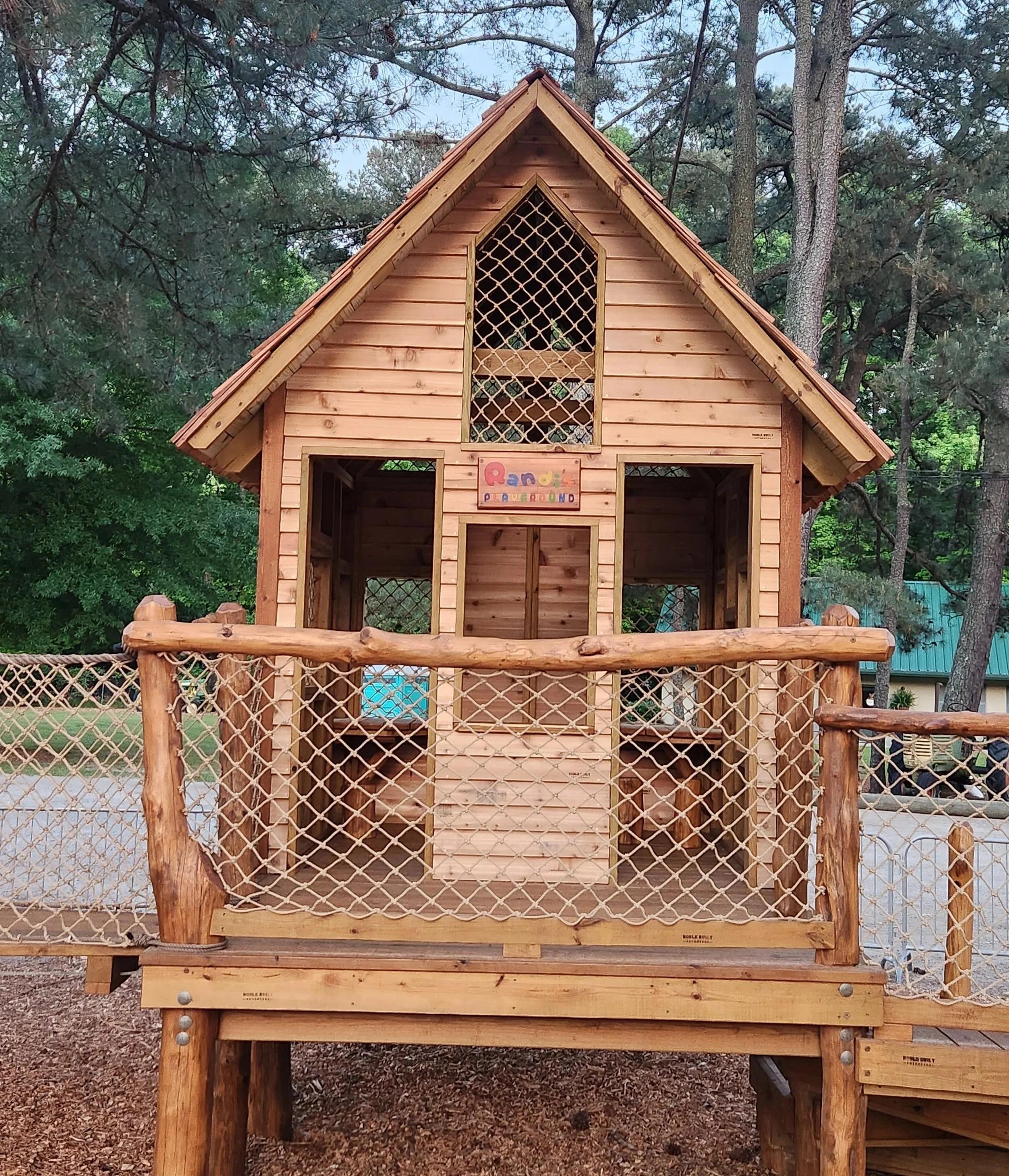Large treehouse playground at Hunt Club Farm with two bird's nests, a sky net, cargo climbers, suspension and plank bridges, a climbing wall, slide, and connected play decks in Virginia Beach, Virginia.