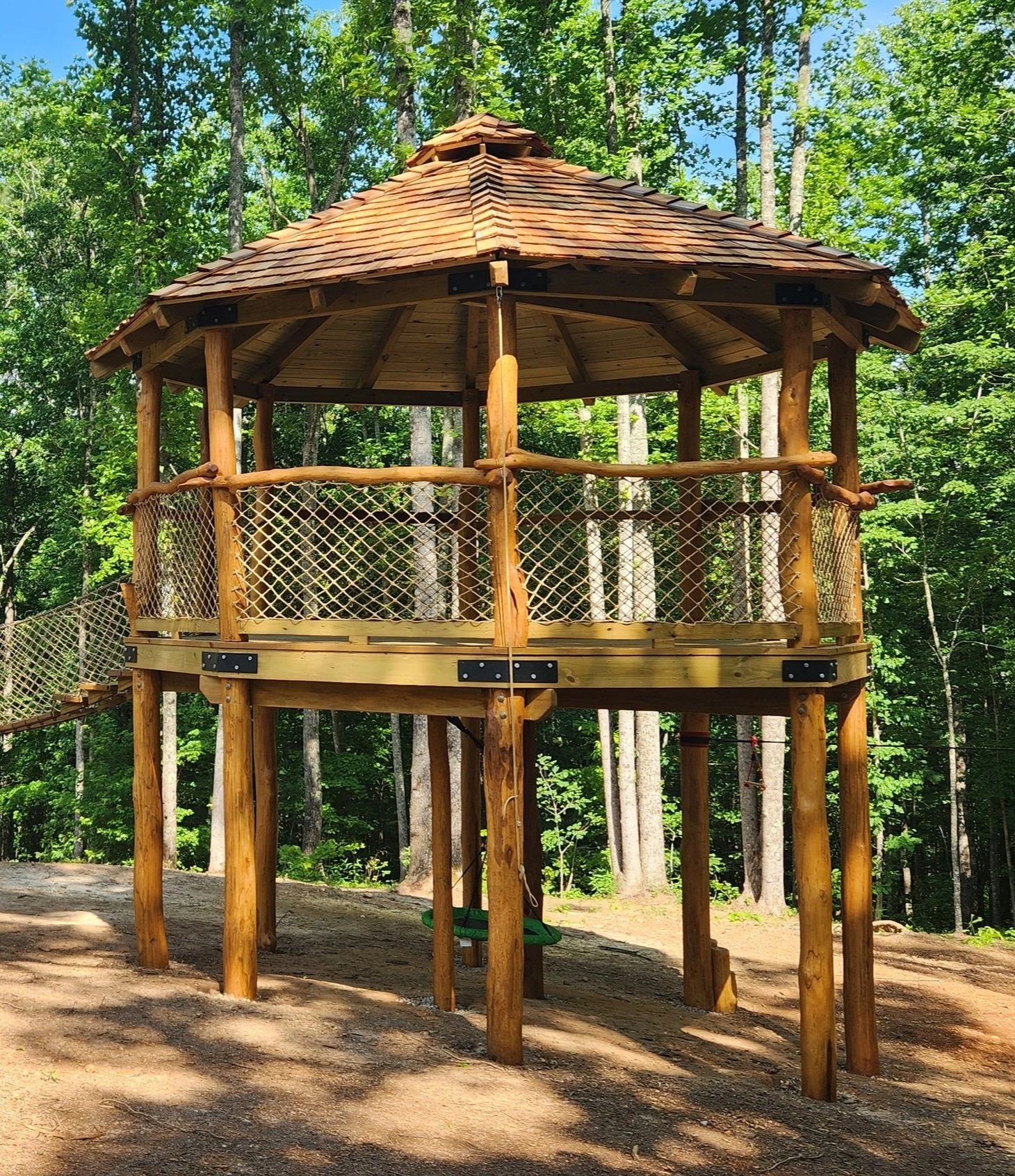 Family gathering deck with a suspension bridge, climbing wall, stairs, slide, and small connecting deck in Talking Rock, Georgia.