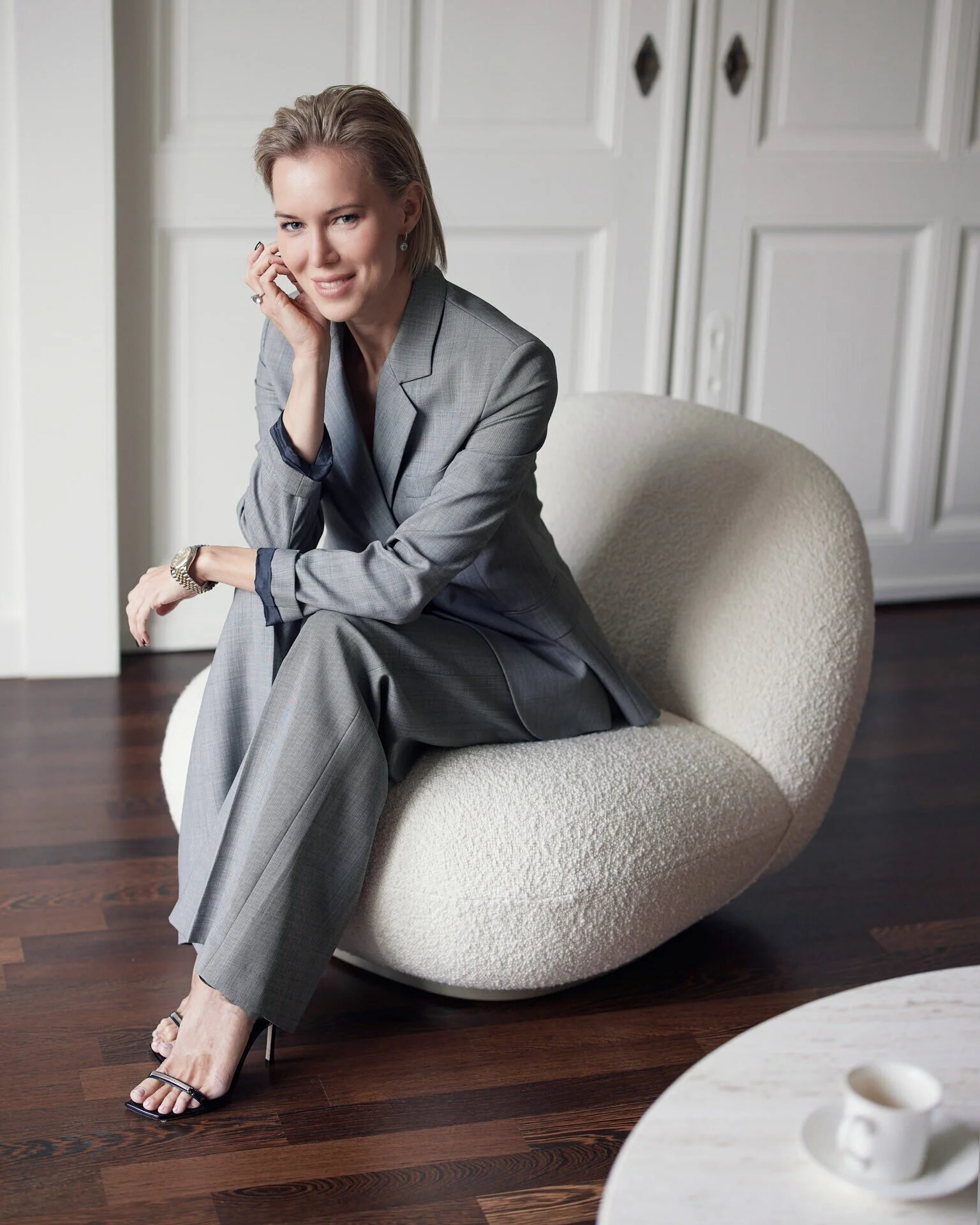 Woman_in_Grey_Suit_Sitting_on_White_Chair.jpeg