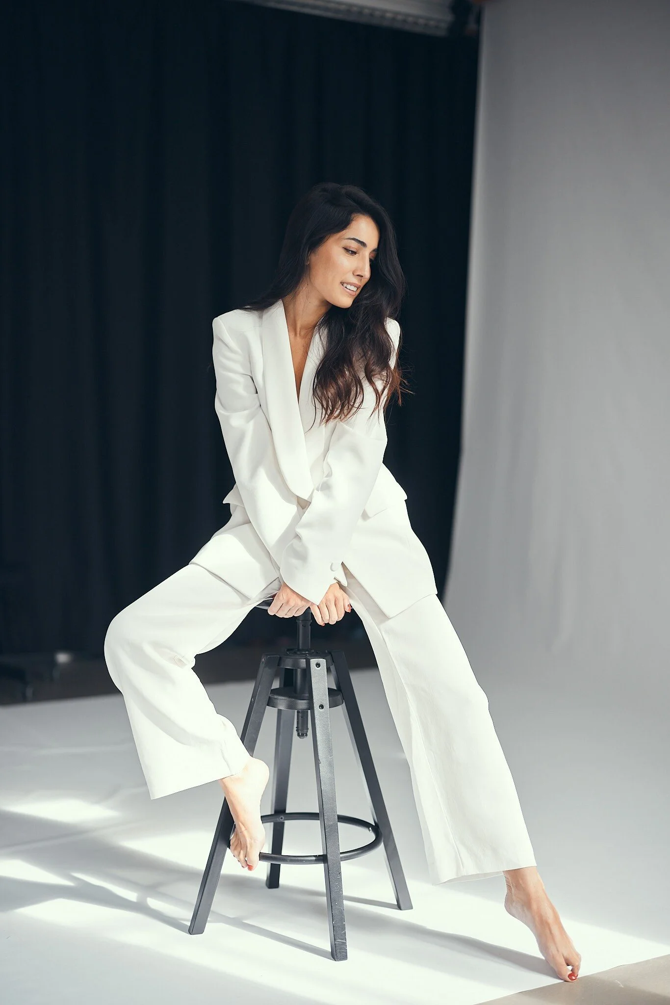 Woman_in_white_suit_sitting_on_stool_with_bare_feet.jpg