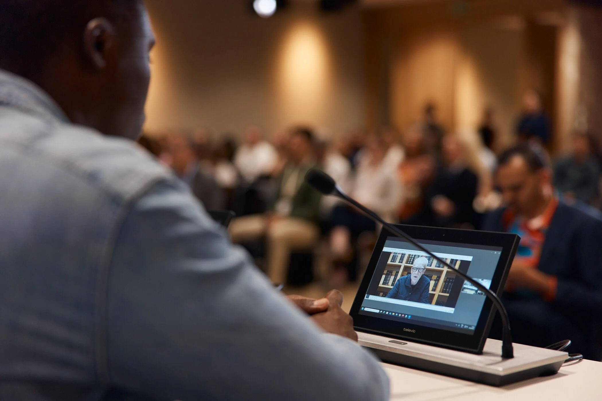 Man_in_denim_shirt_at_conference_with_laptop_display.jpg
