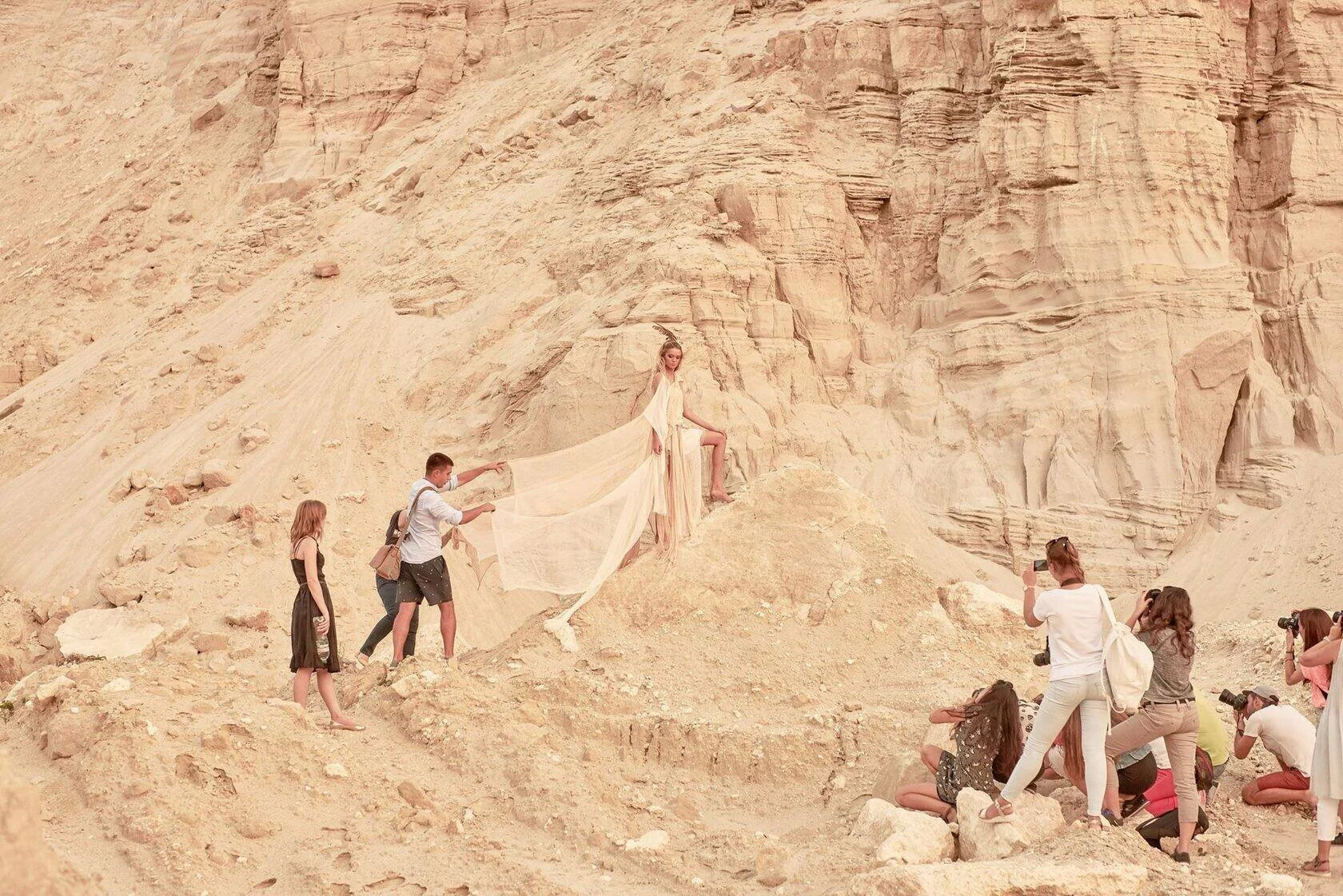 Model_in_flowing_dress_on_rocky_terrain_with_photographers.jpg