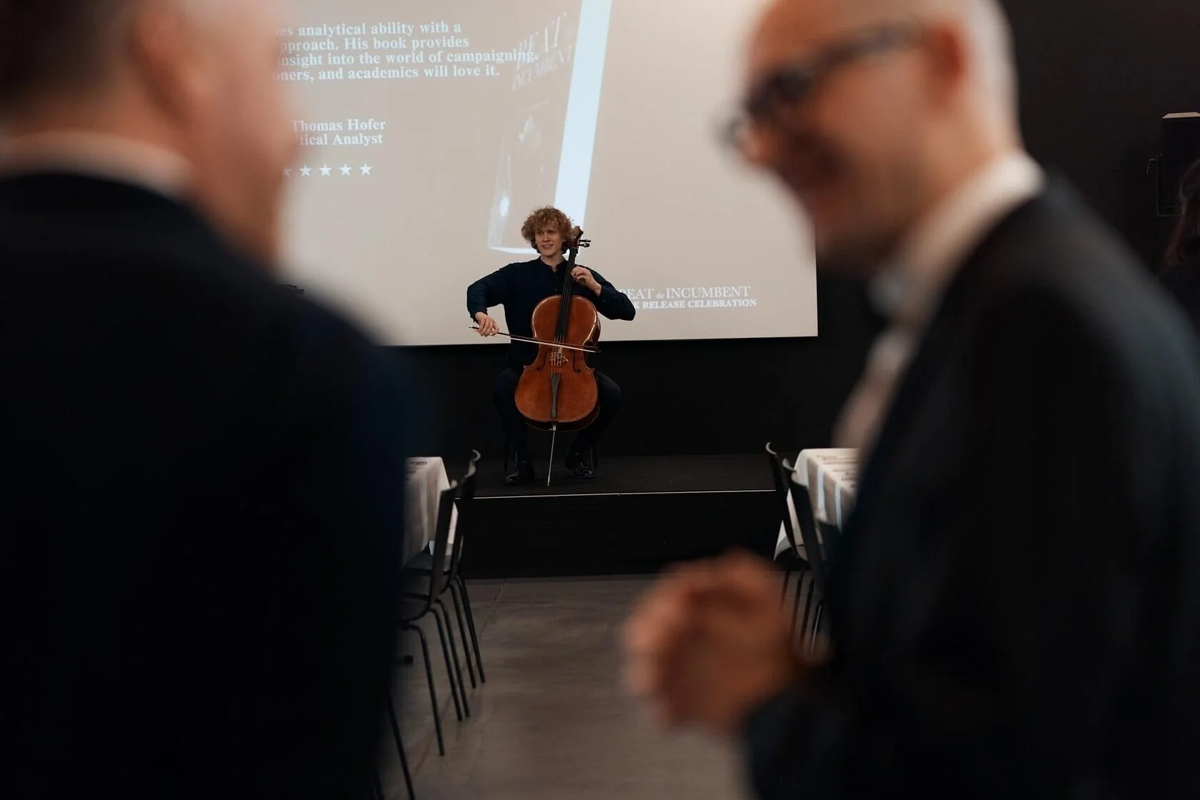 Cellist_Performing_at_Event_with_Audience_in_Background.jpeg