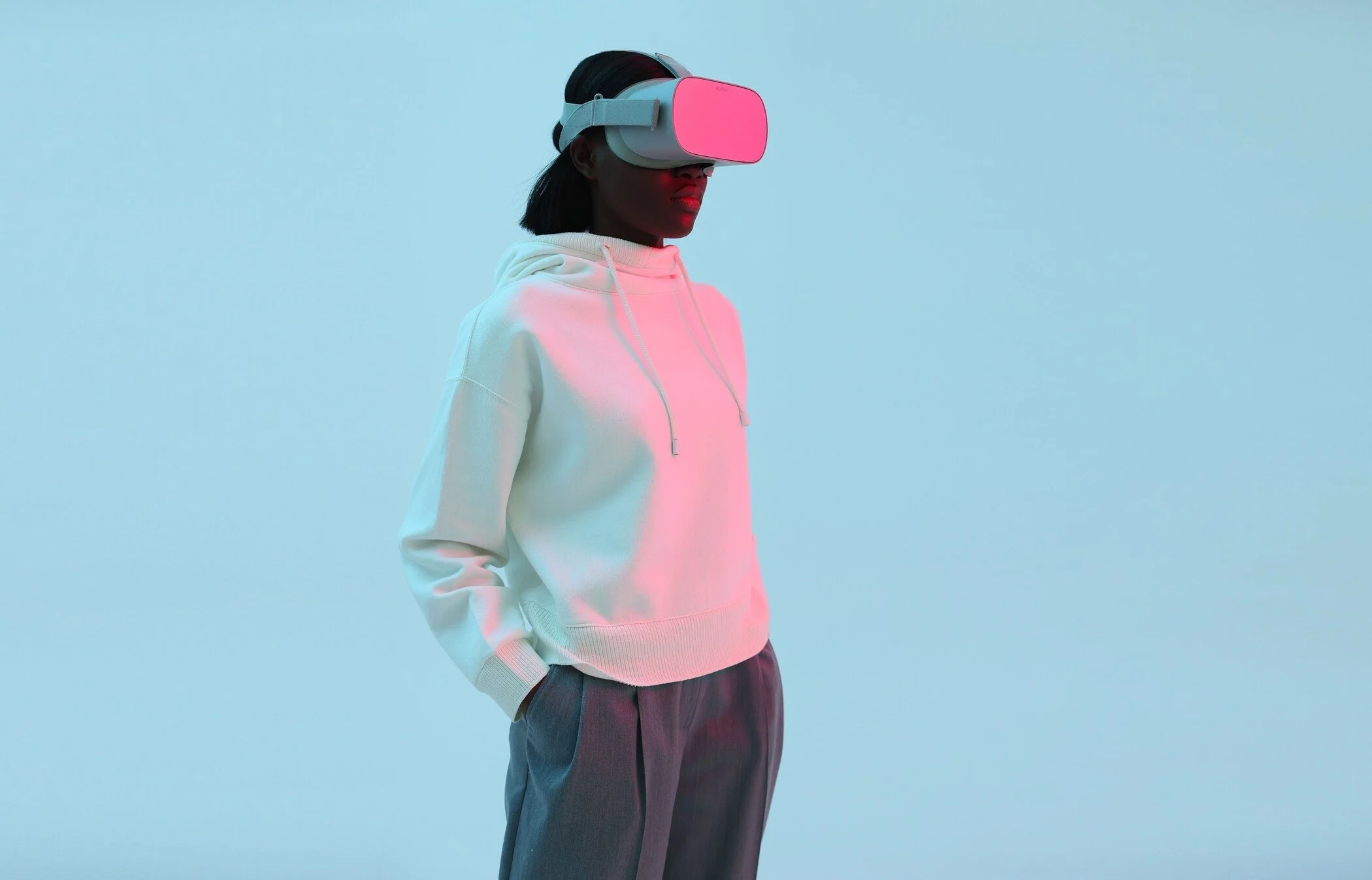Person_in_white_hoodie_with_VR_headset_against_blue_background.jpg
