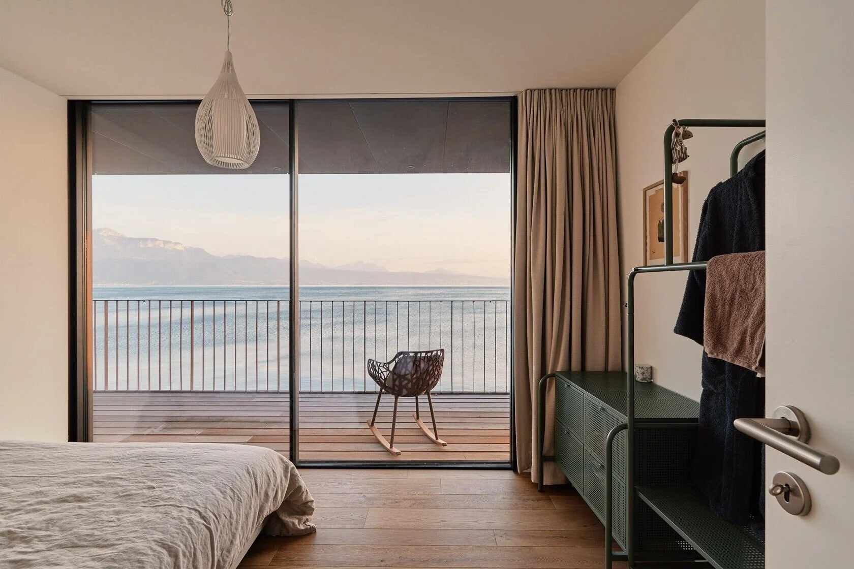 Modern_bedroom_with_lake_view_and_rocking_chair.jpeg