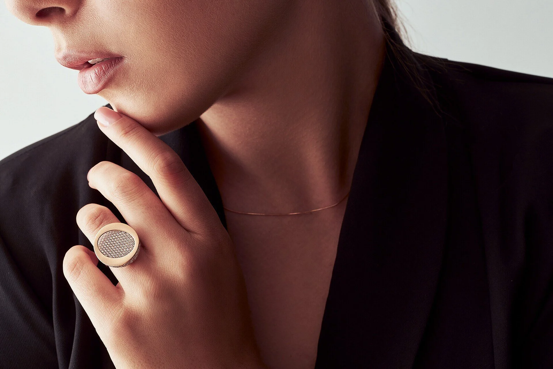L'image montre un gros plan d'une main avec une bague et un collier délicat sur une tenue noire. Capturée à Zürich par un photographe professionnel.