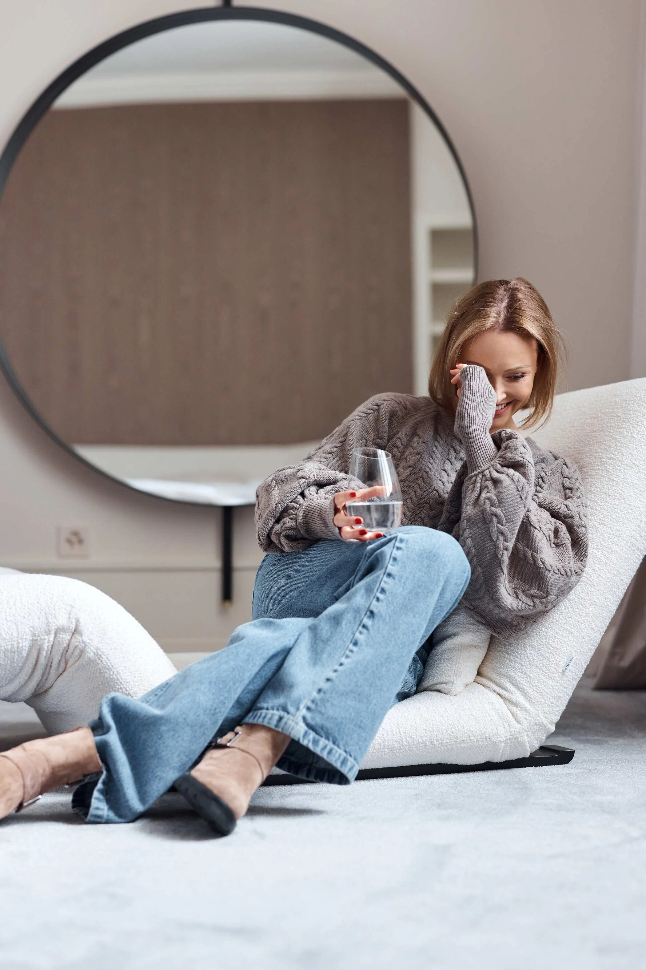 Woman_in_cozy_sweater_and_jeans_holding_glass_in_modern_setting.jpg
