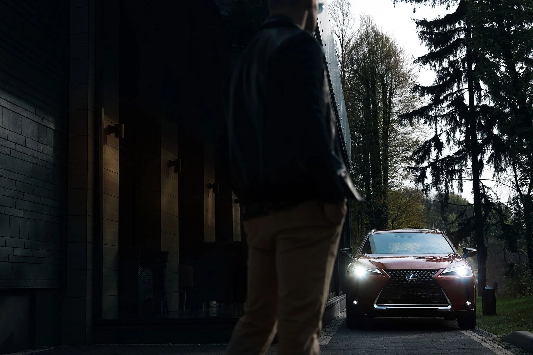 Homme en blouson de cuir près de la voiture Lexus dans un décor ombragé.jpg