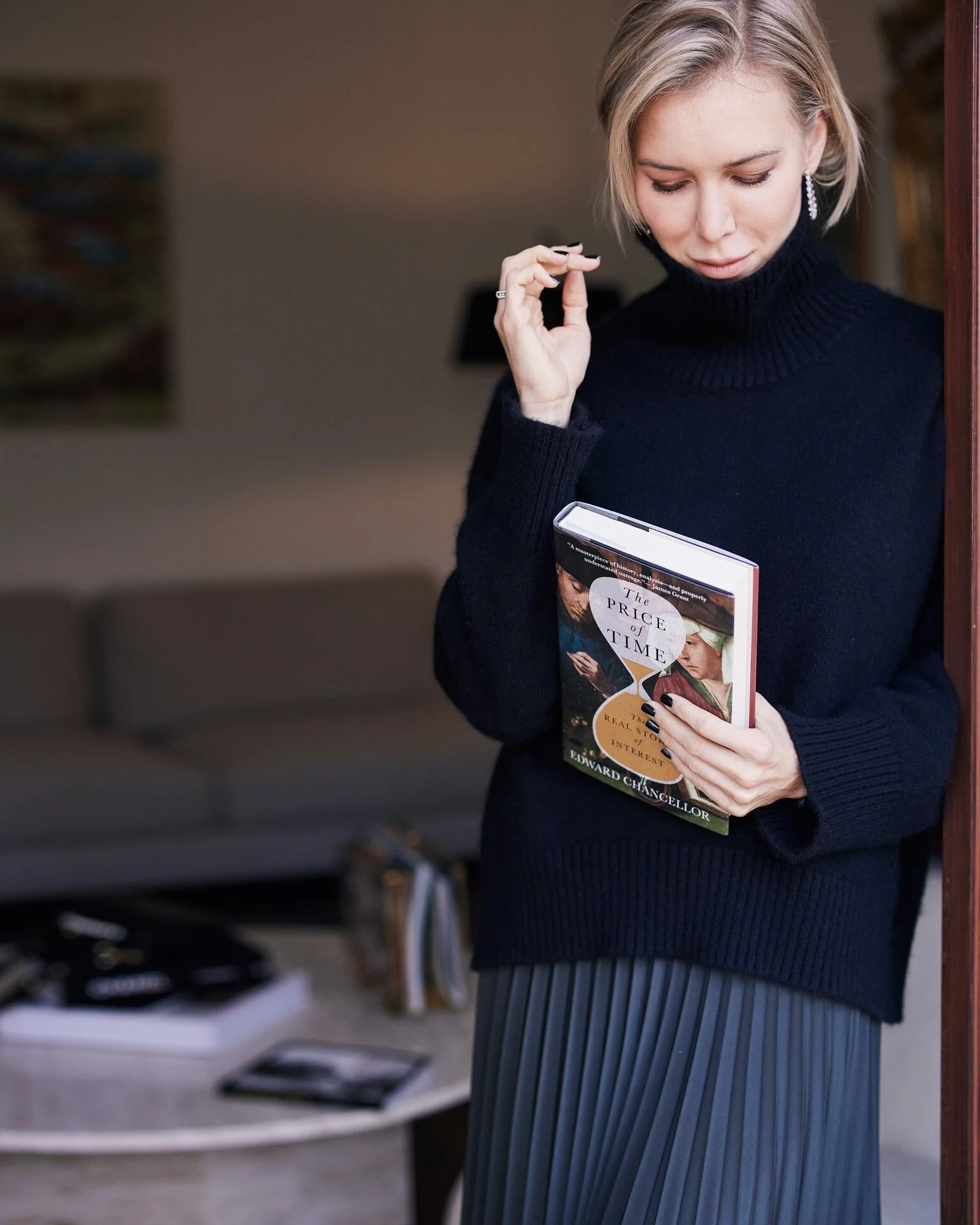 Woman_in_Black_Sweater_Holding_Book_in_Modern_Interior.jpeg