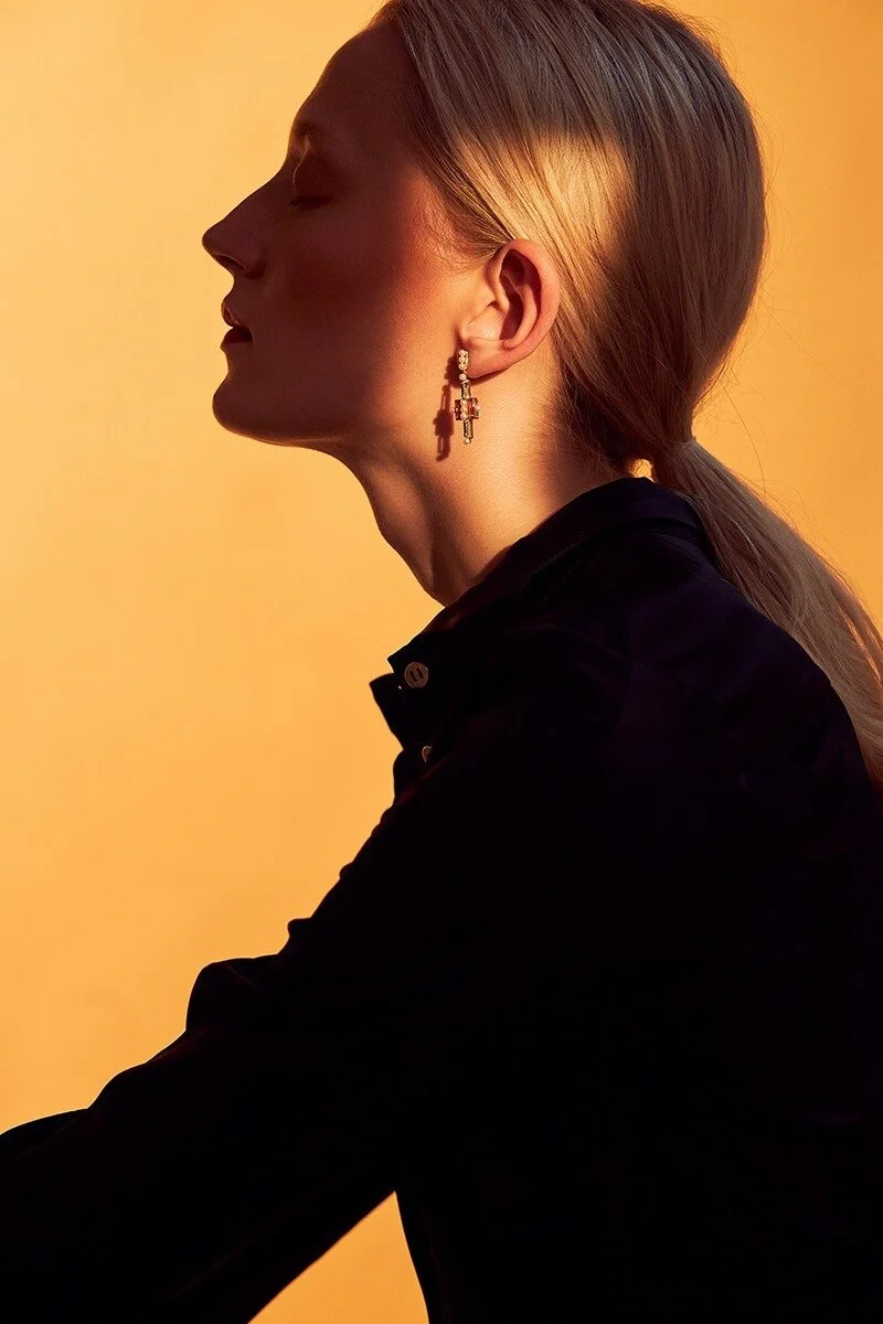 Profile_of_woman_with_earrings_against_orange_background.jpg
