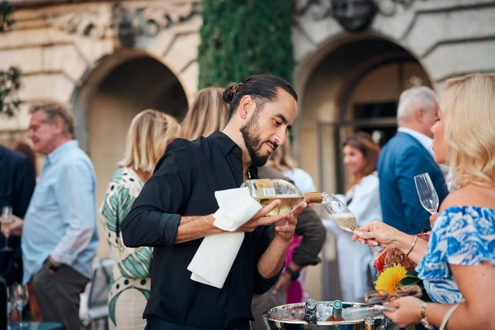 Man_in_black_shirt_pouring_wine_at_outdoor_event.jpeg