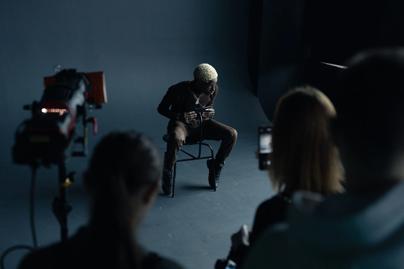 Man_in_brown_outfit_seated_on_chair_in_studio_setting.jpg