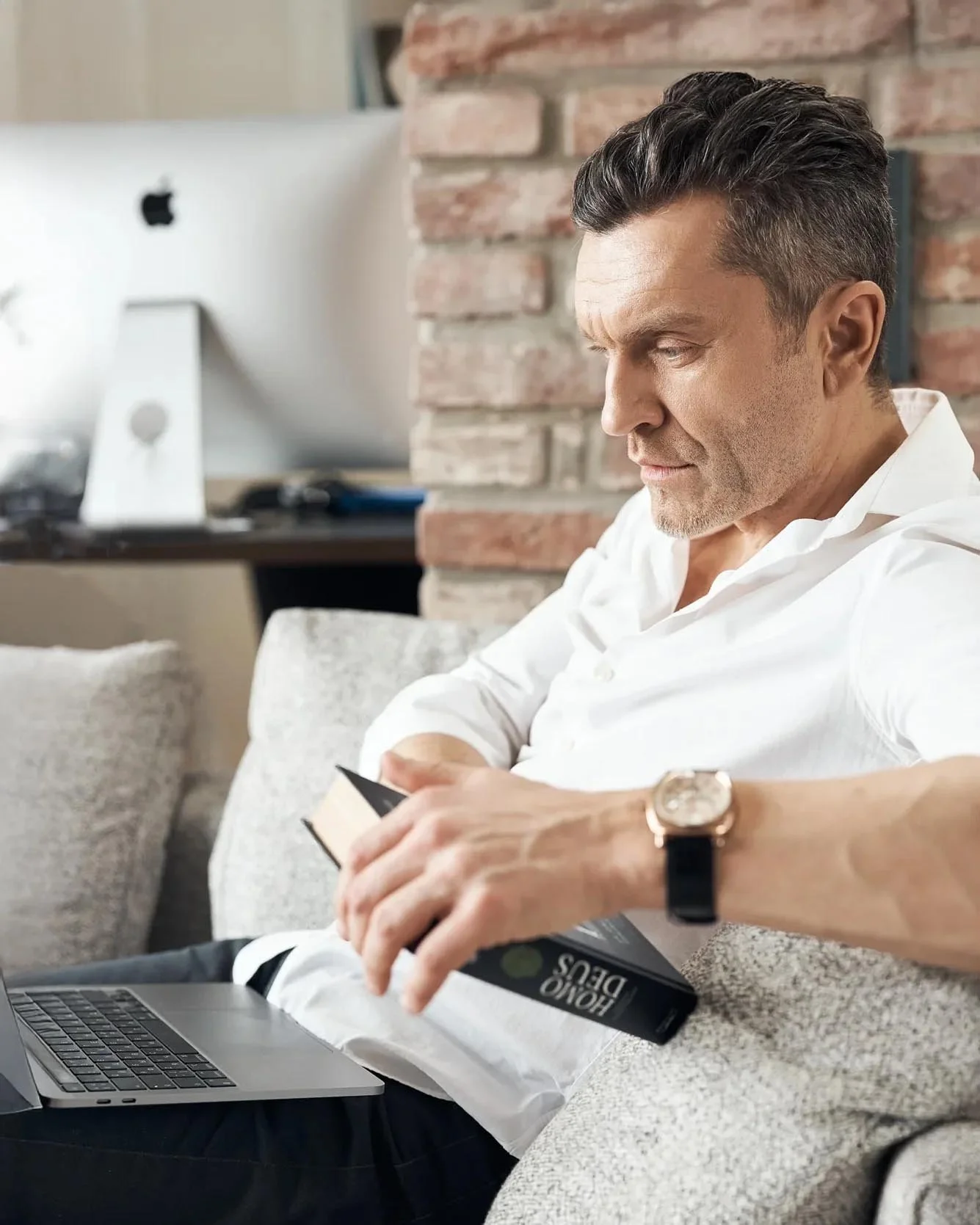Man_in_White_Shirt_Reading_on_Couch_with_Laptop.jpg