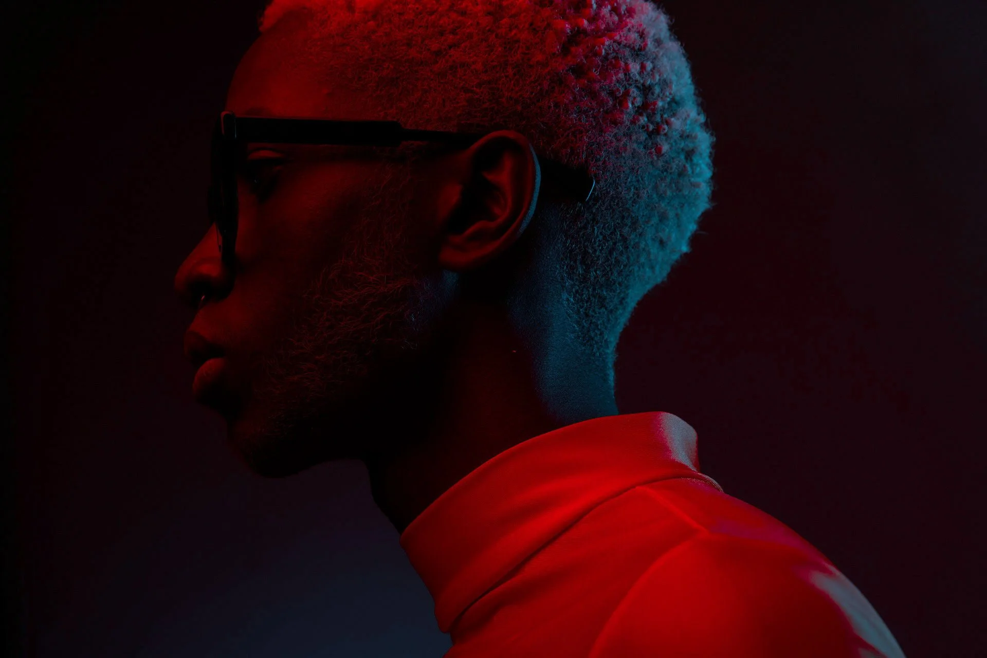 Profil d'un homme avec des lunettes et des cheveux clairs dans une lumière rouge.jpg