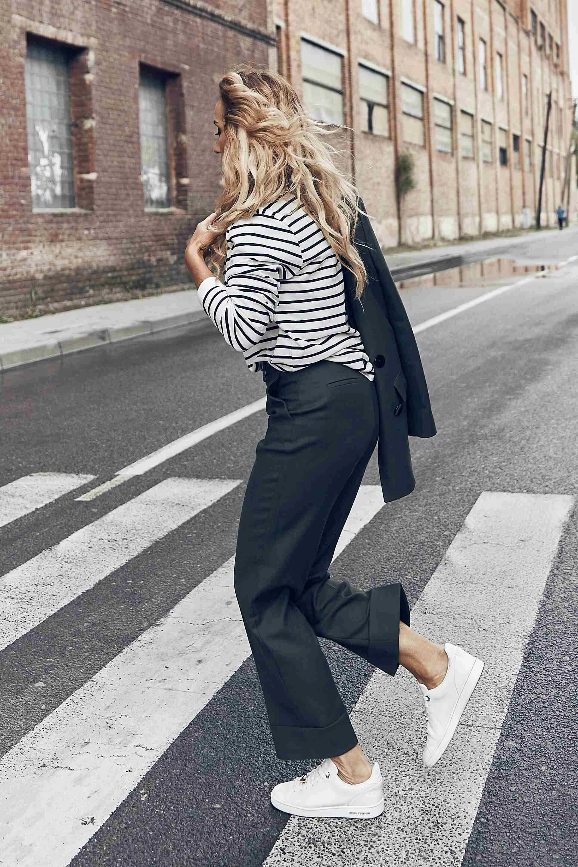 Woman_in_Striped_Shirt_and_Black_Pants_Walking_on_Street.jpg