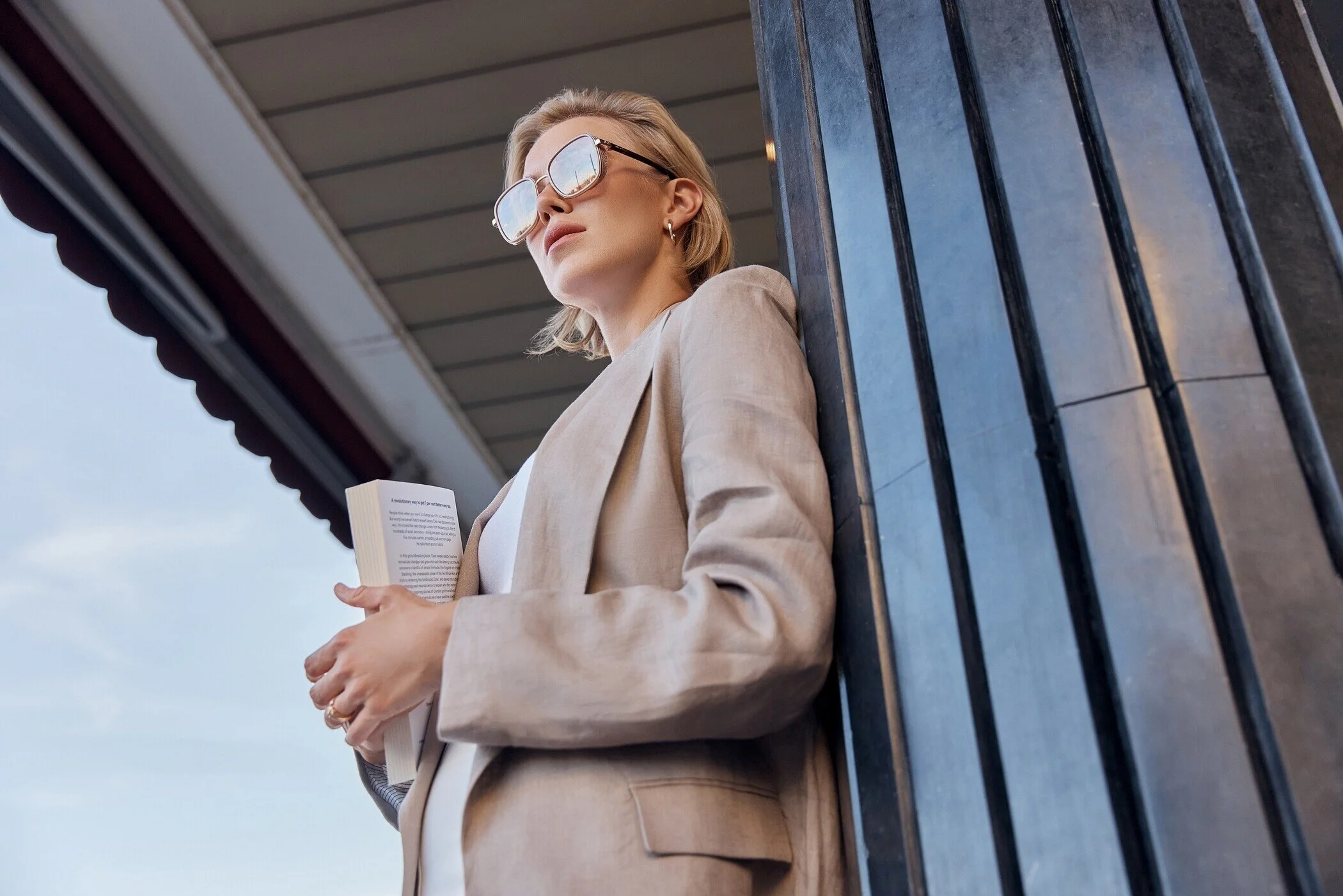 Woman_in_beige_blazer_holding_a_book_outdoors.jpg