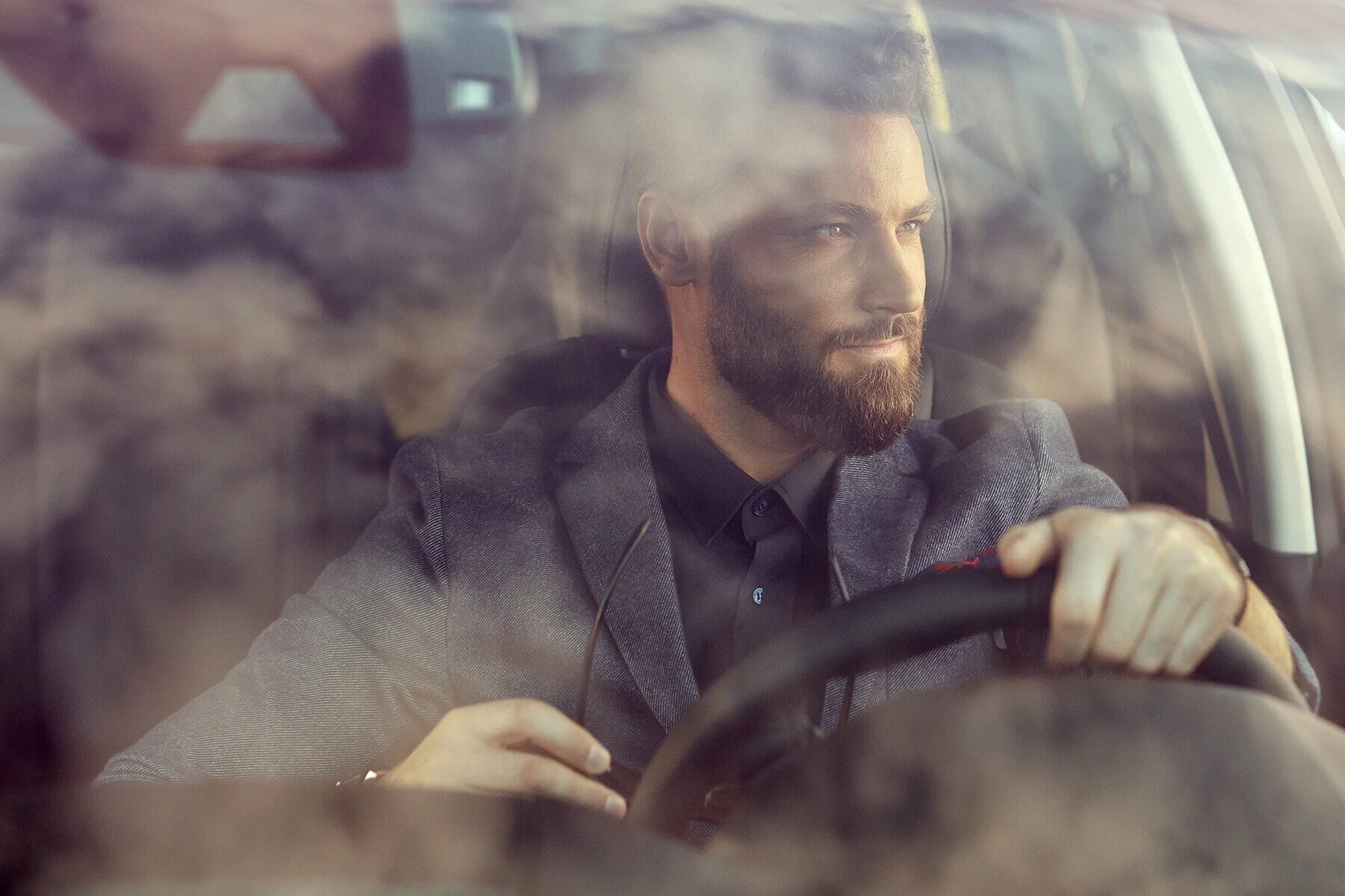 Man_in_suit_driving_car_with_sunglasses_in_hand.jpg