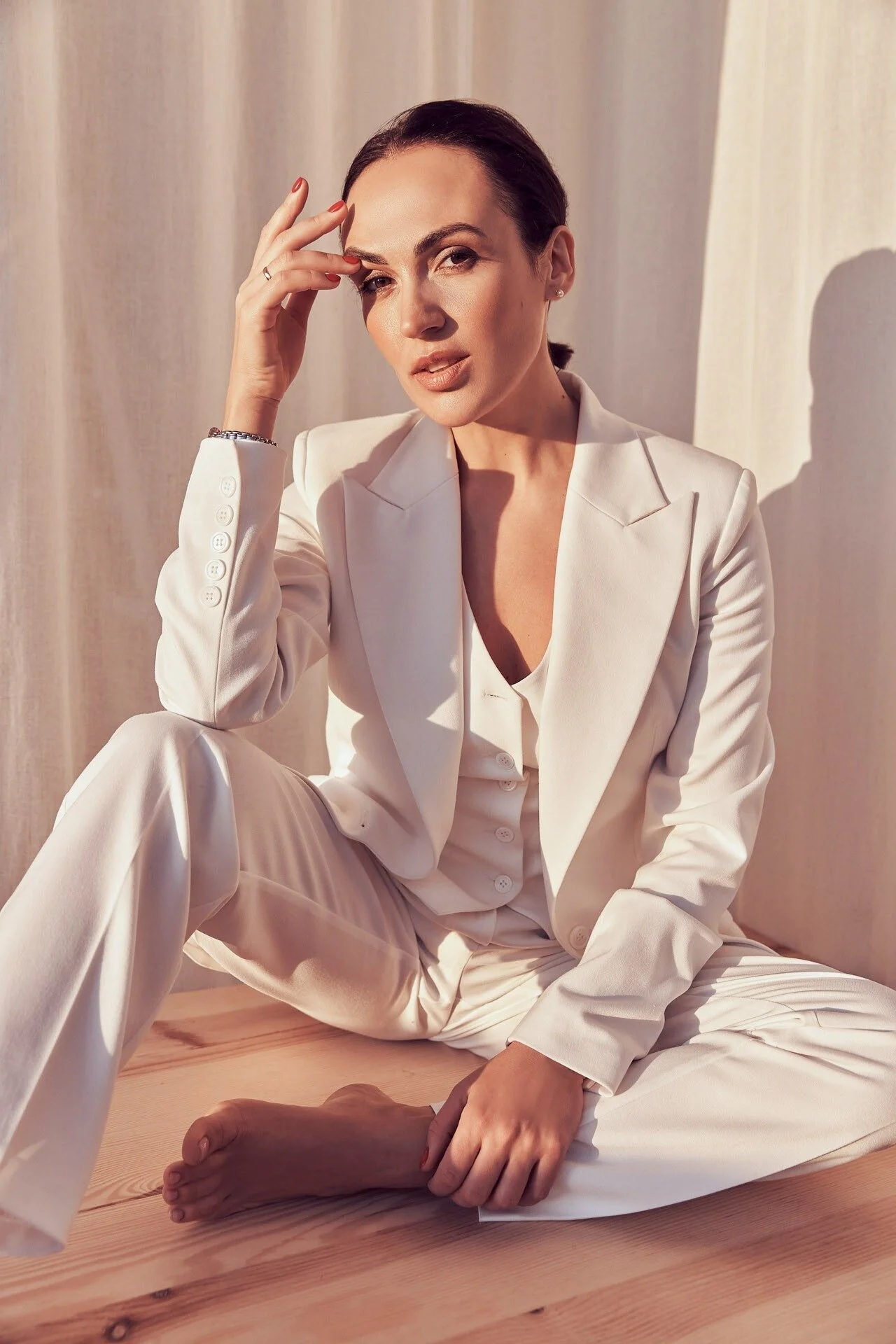 Woman_in_white_suit_sitting_on_wooden_floor_with_soft_light.jpeg