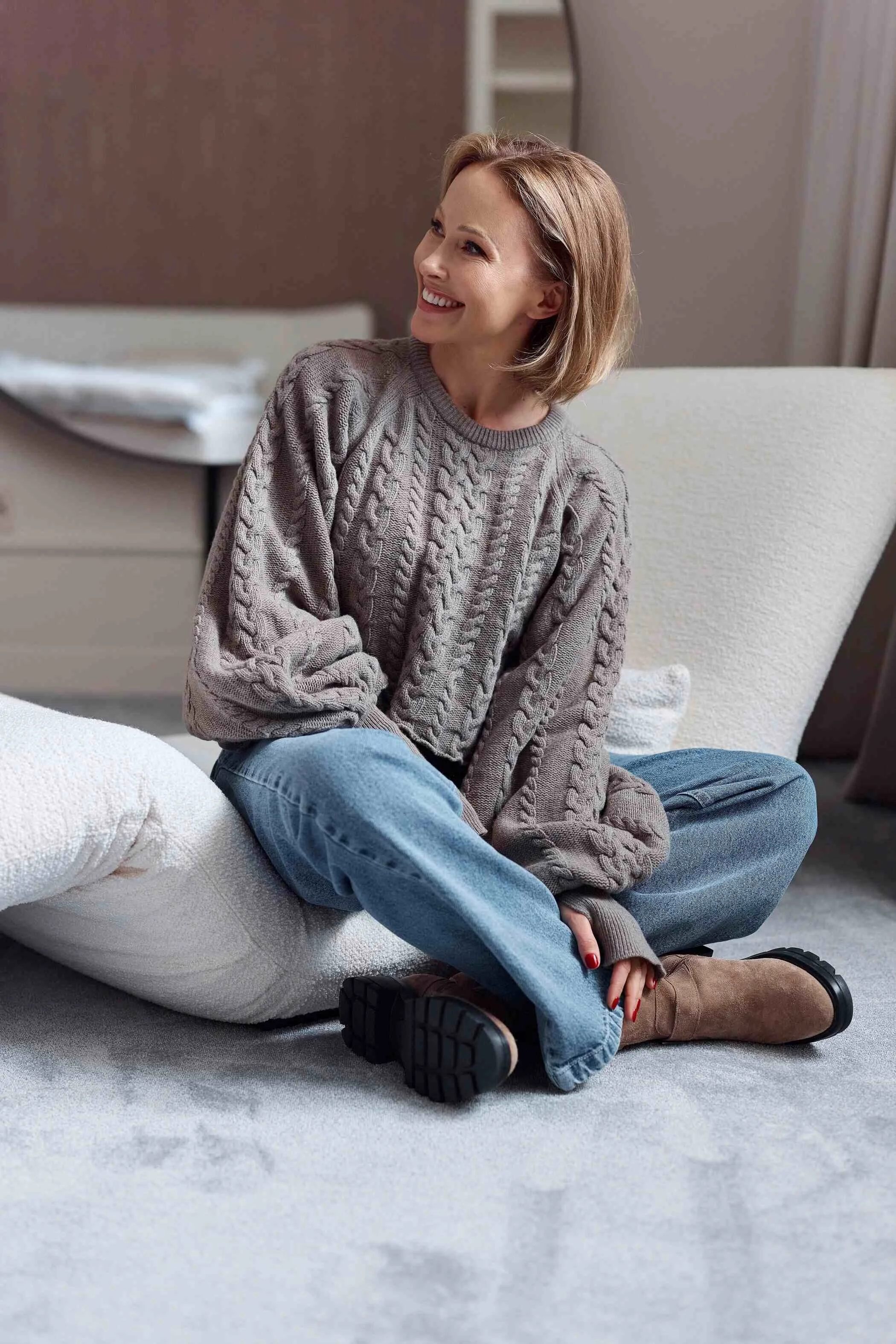 Woman_in_grey_sweater_and_blue_jeans_sitting_on_a_sofa.jpg
