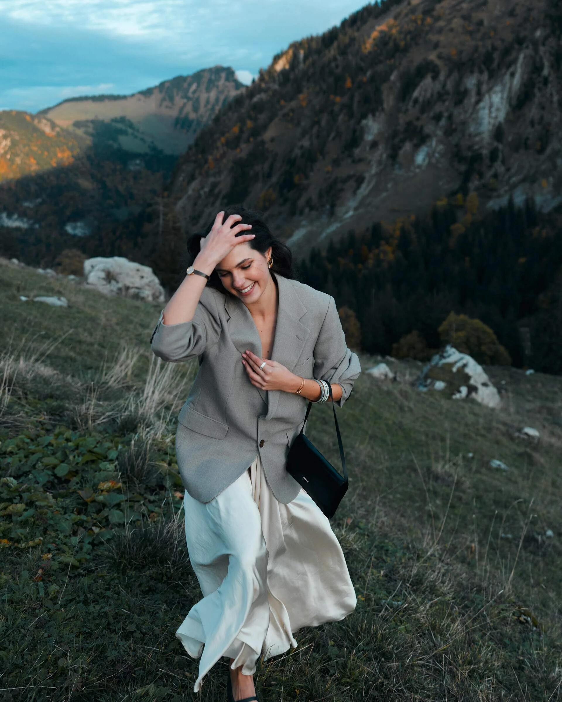 Woman_in_blazer_and_skirt_walking_in_mountainous_landscape.jpg