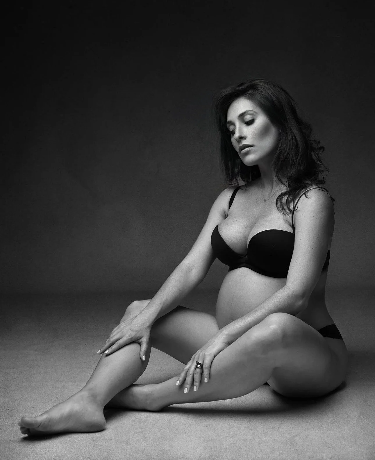 Pregnant_woman_in_black_lingerie_seated_against_dark_backdrop.jpeg