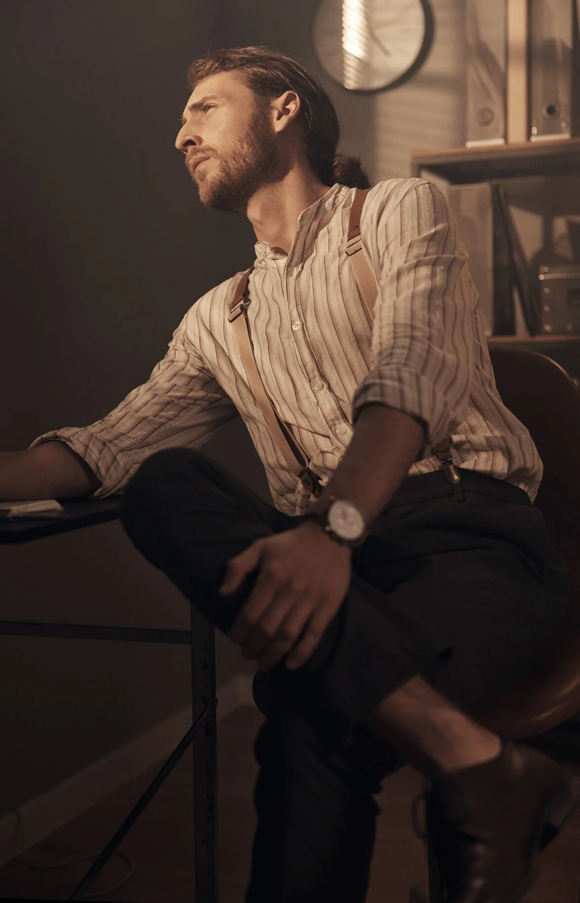 Man_in_striped_shirt_with_suspenders_seated_at_desk.jpeg