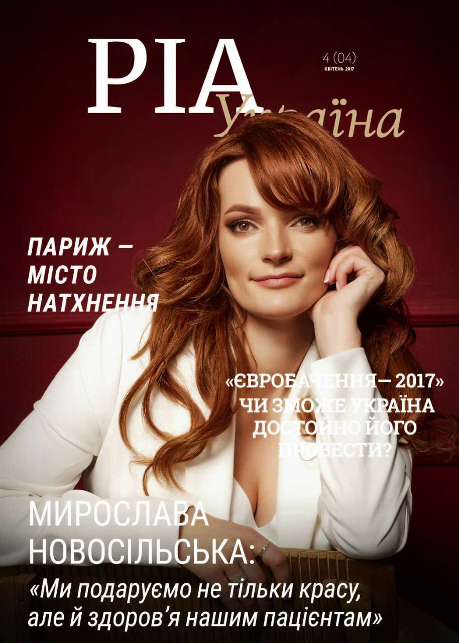 Woman_in_white_blazer_with_red_hair_against_dark_background.jpg