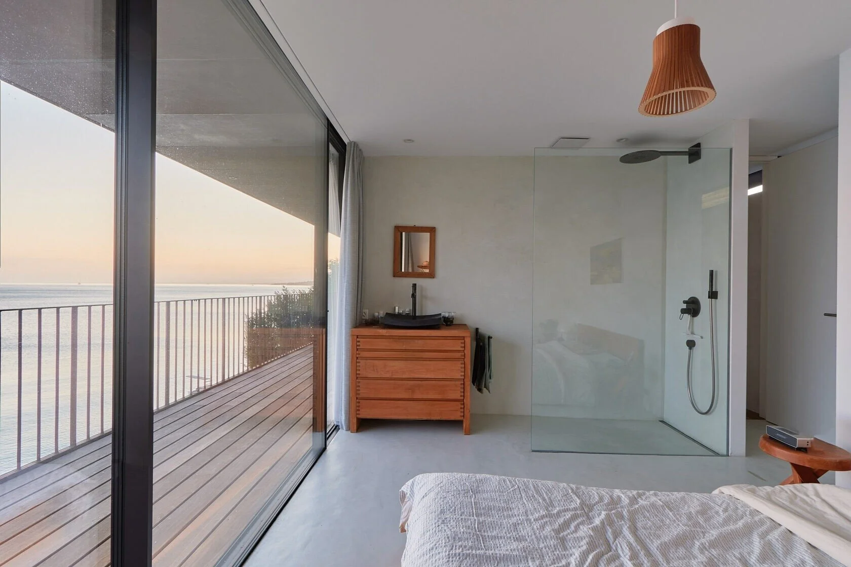 Modern_bedroom_with_glass_shower_and_wooden_furniture.jpeg