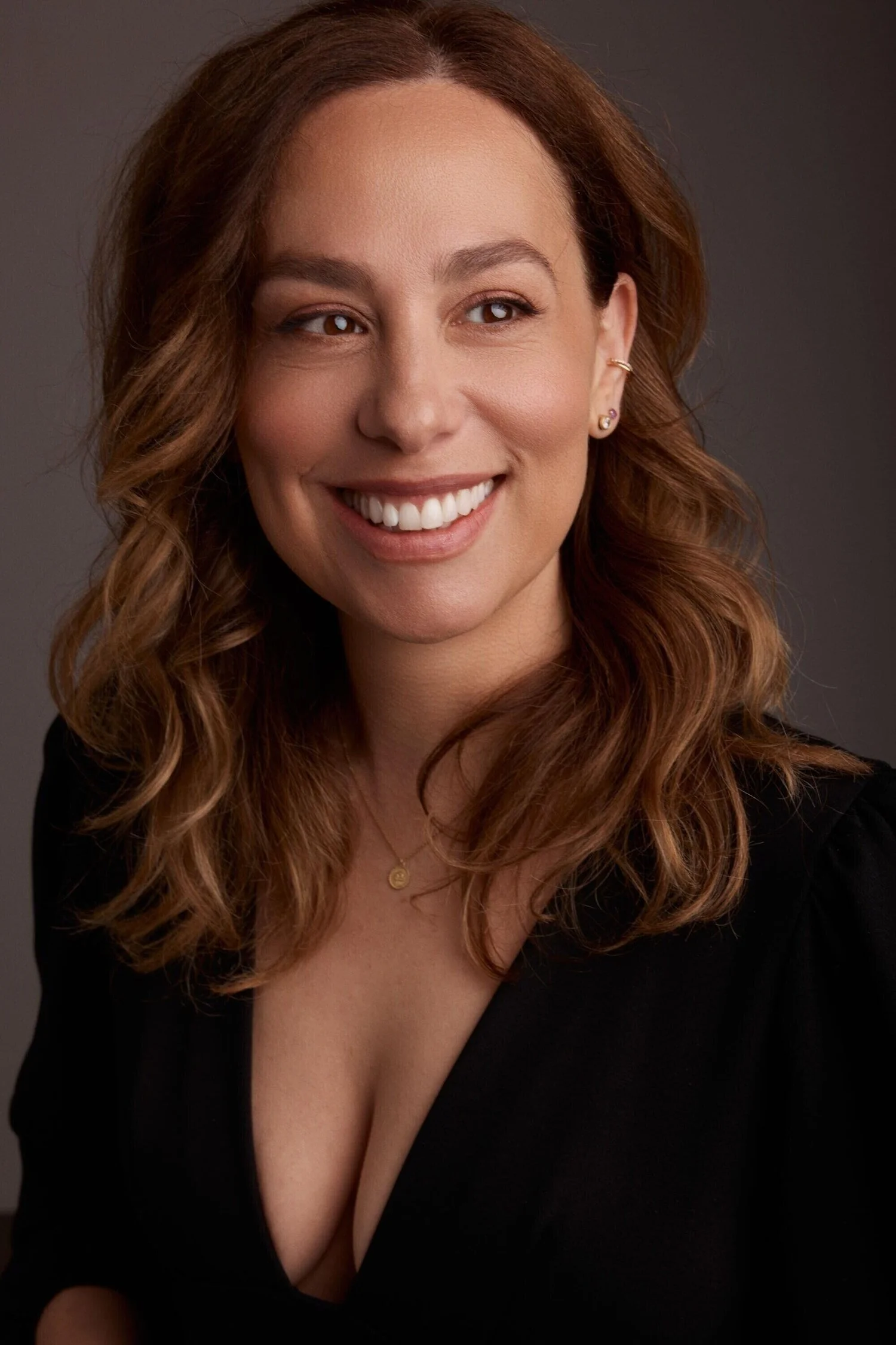 Smiling_woman_in_black_dress_with_wavy_hair.jpg