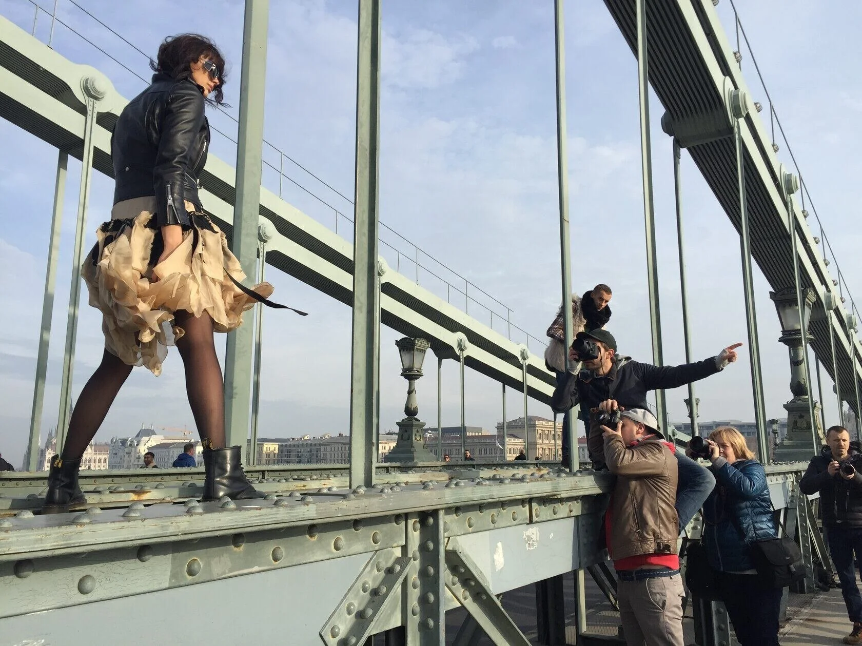 Mannequin de mode marchant sur un pont pendant que des photographes prennent des photos d'elle.