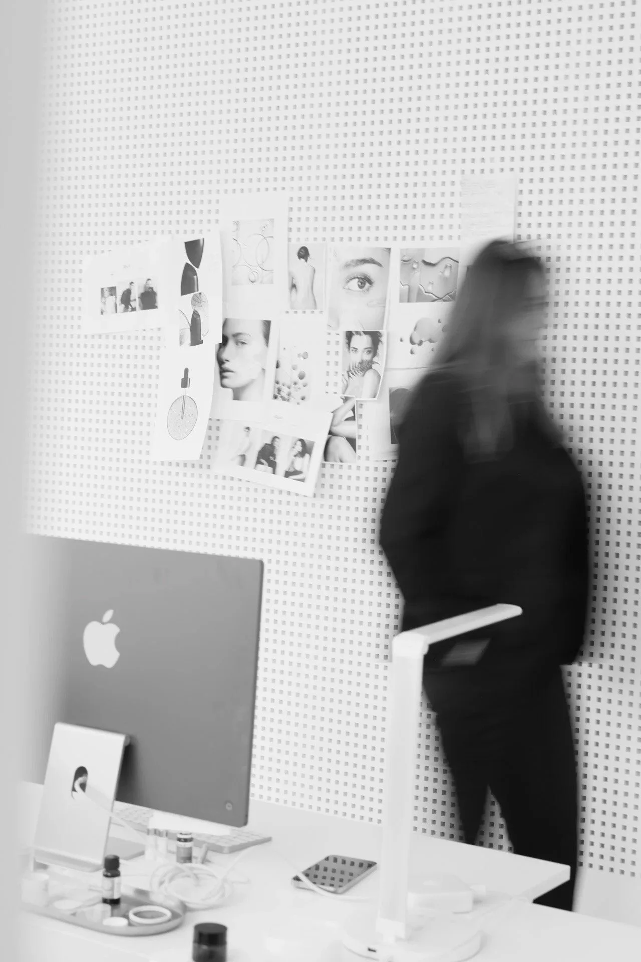 Woman_in_black_coat_walking_past_photo_wall_in_studio.jpg