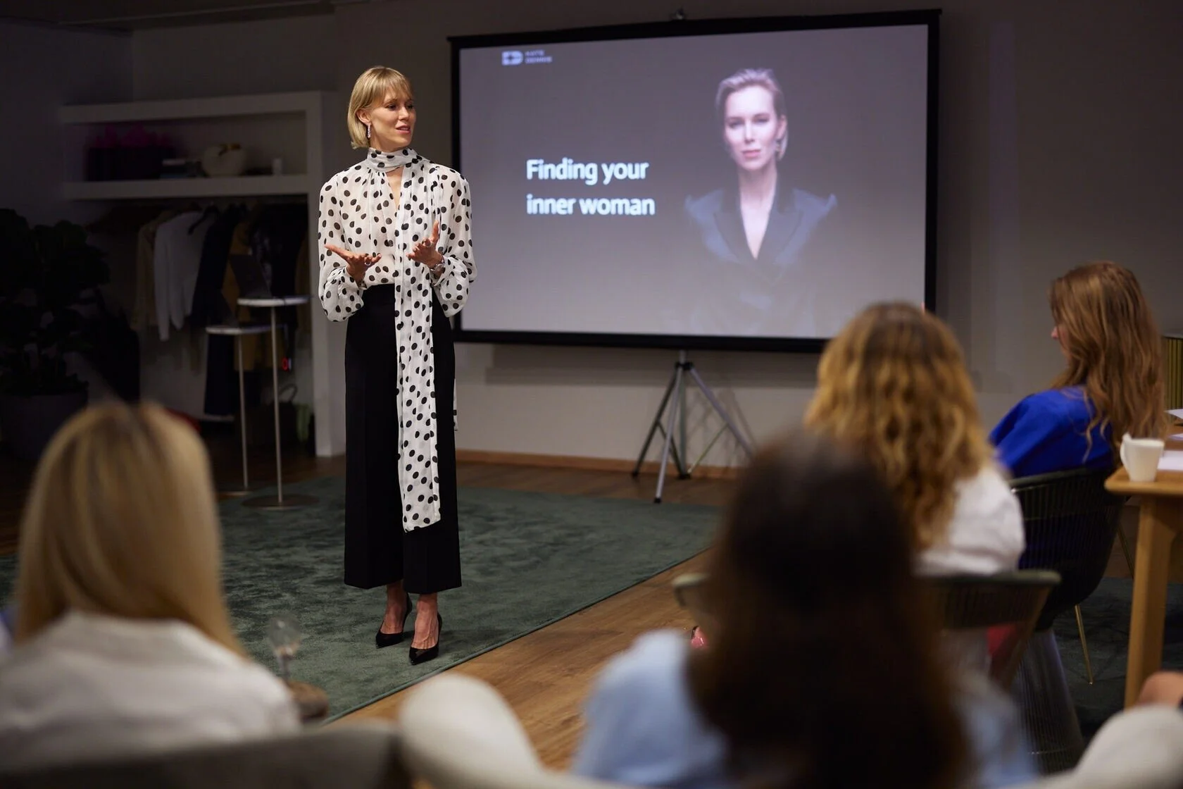 Woman_in_Polka_Dot_Blouse_Speaking_at_Presentation.jpeg