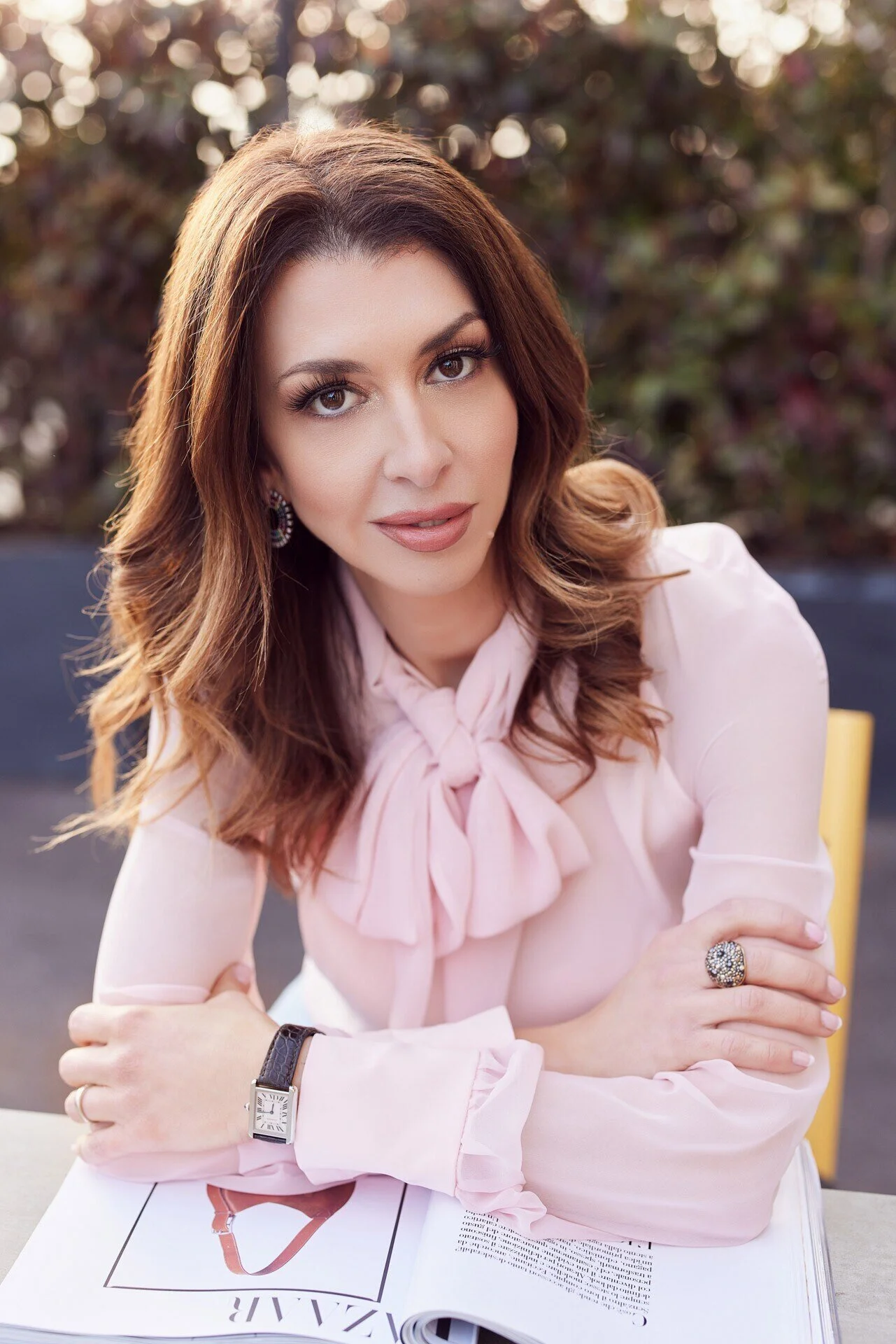 Woman_in_pink_blouse_with_magazine_outdoors.jpeg