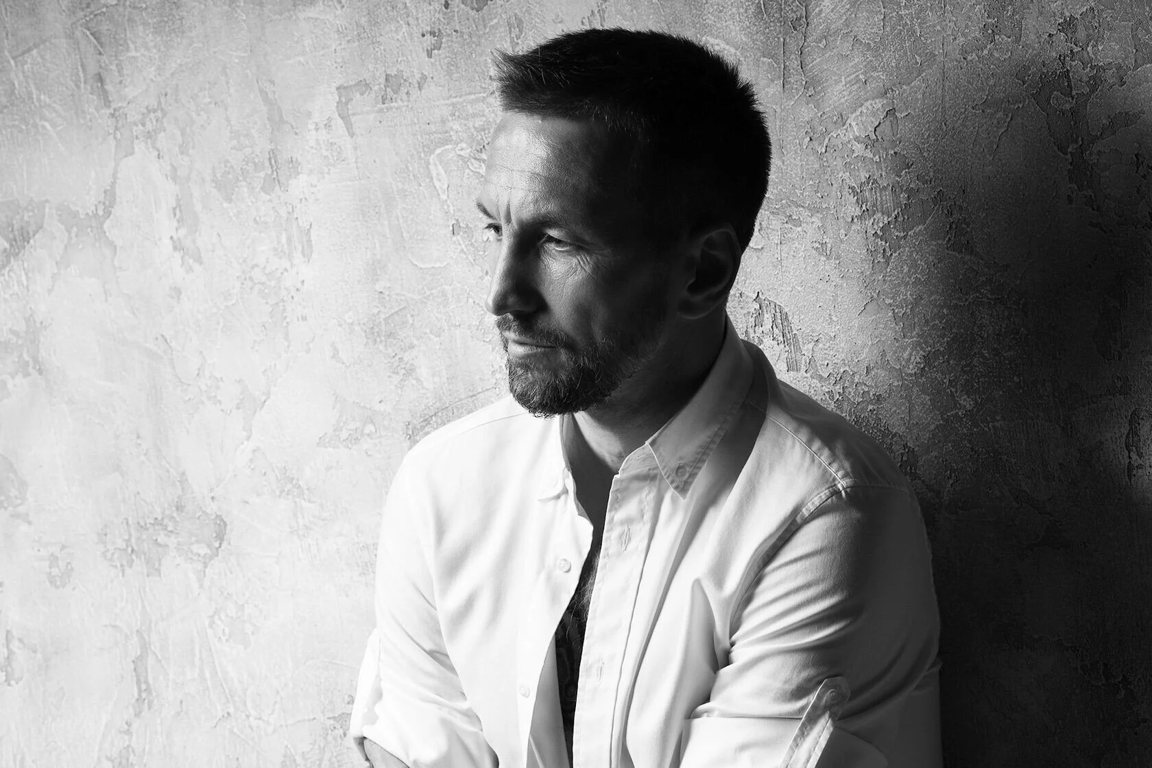 Man_in_white_shirt_against_textured_wall_side_profile.jpg