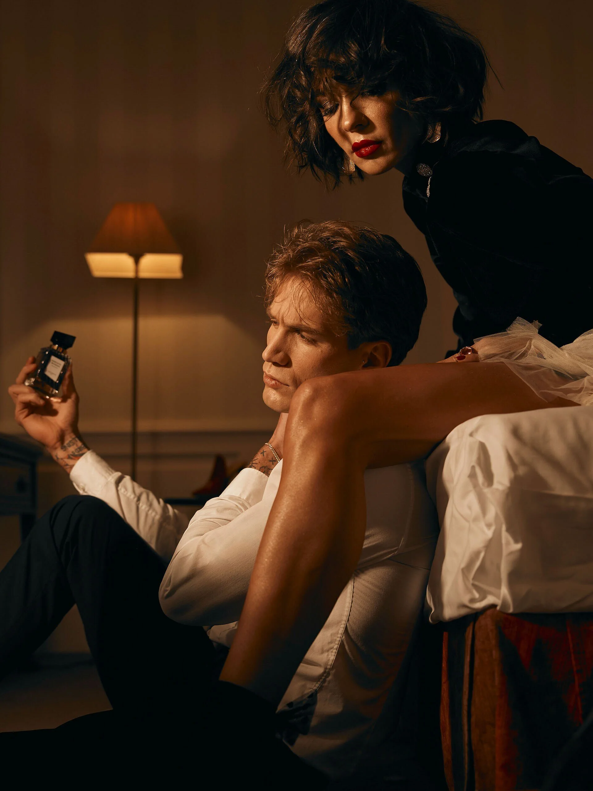 Un homme est assis par terre et une femme se penche sur lui, tenant un flacon de parfum. Capturé à Zurich par un photographe portraitiste professionnel.