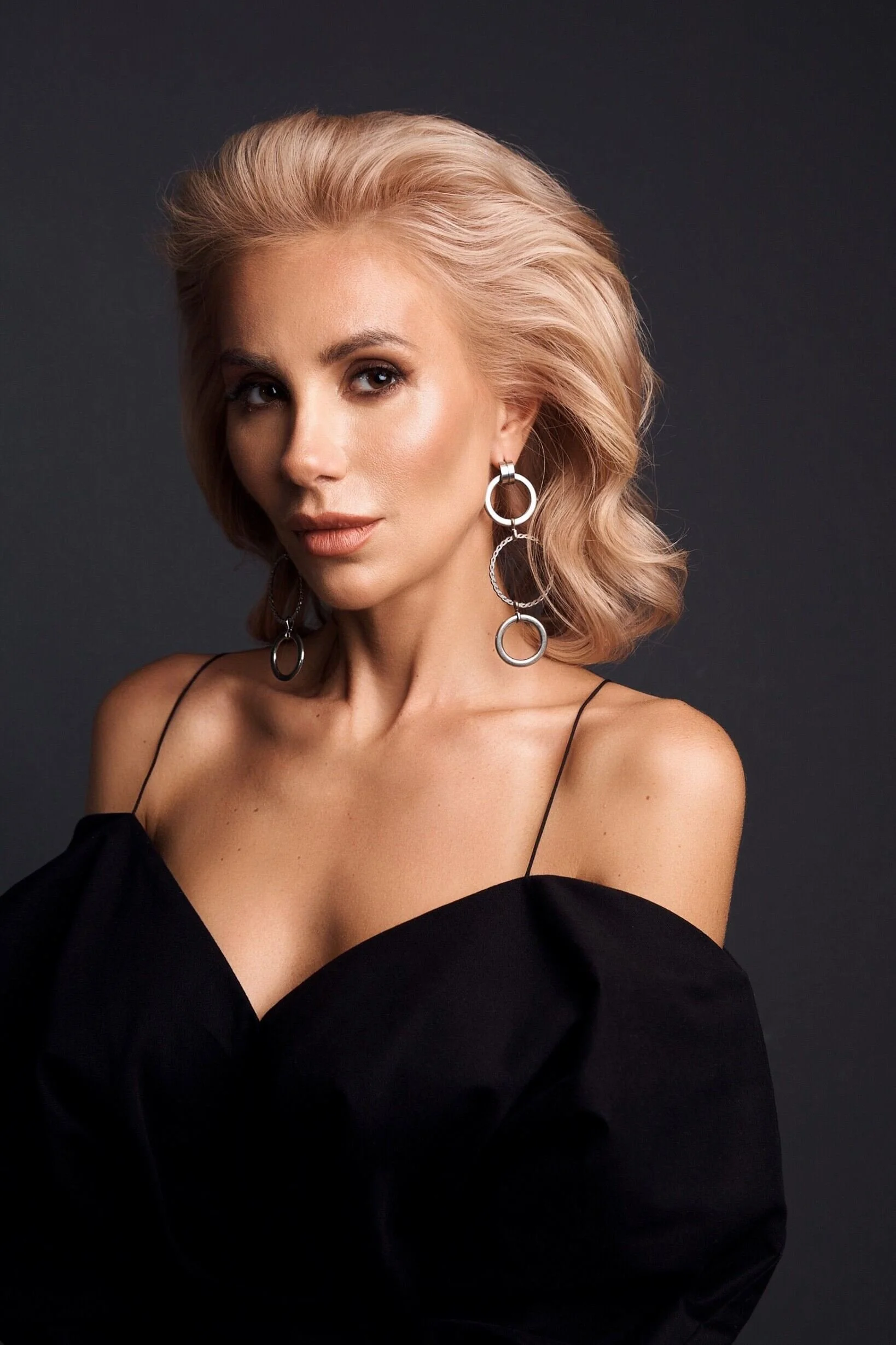 Woman_in_Black_Dress_with_Silver_Earrings_Against_Dark_Background.jpeg