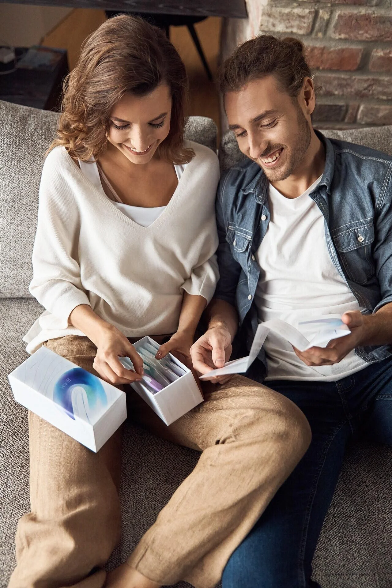 Un couple est assis sur un canapé, examinant des objets colorés dans des boîtes blanches. Cette photo a été prise à Zurich par un photographe professionnel.
